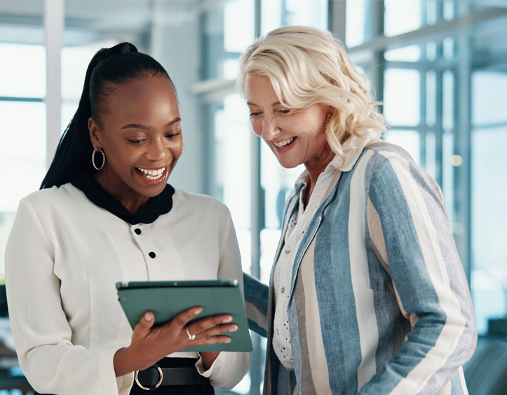 Two professional women looking at reports on tablet